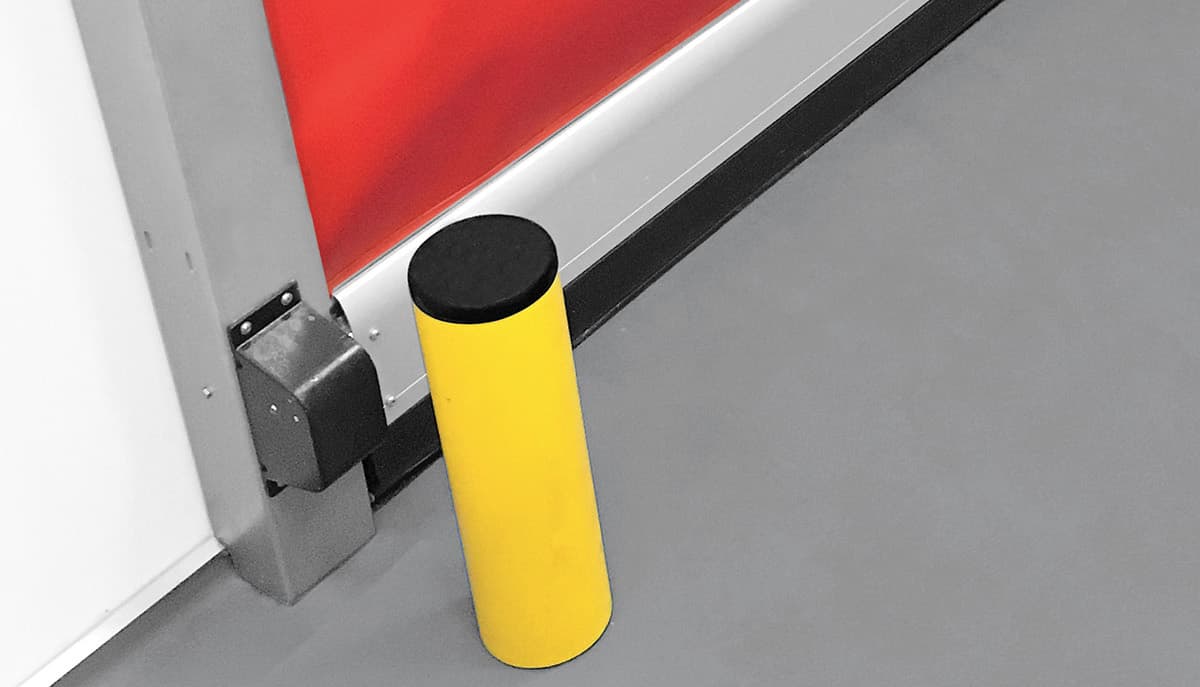 A protection bollard installed beside an industrial door opening