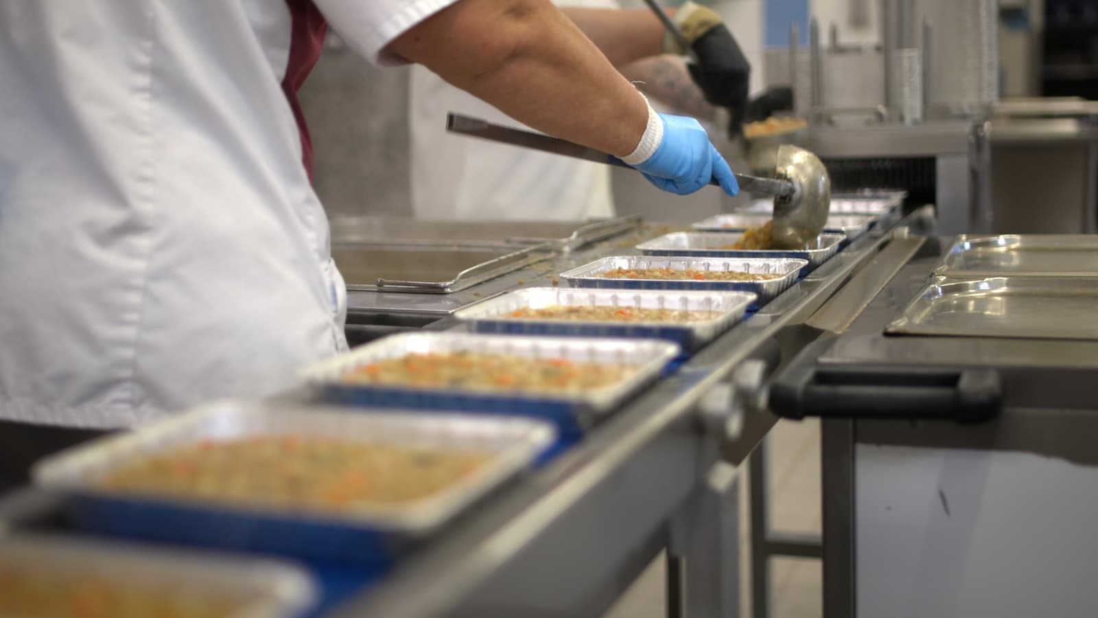 A worker filling trays on a food processing line