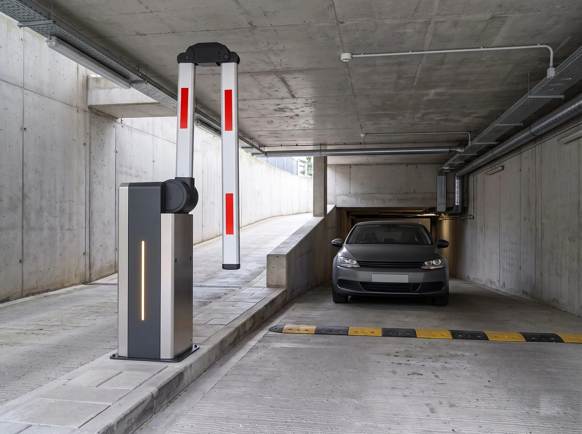 The same folding-arm barrier at the entry ramp of an underground car park with a low concrete ceiling: the boom raised and folded at its knuckle so the outer section hangs vertically under the ceiling, a grey car passing beneath